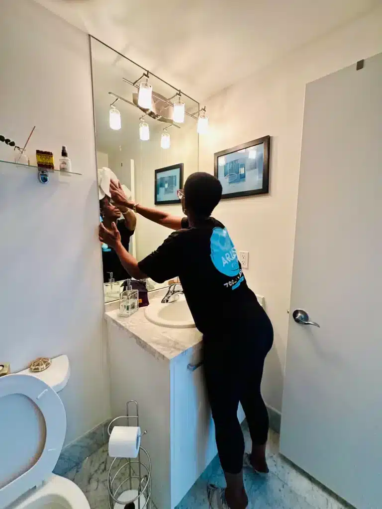 Arionclean cleaner wiping a bathroom mirror, showcasing our 5‑star house cleaning services