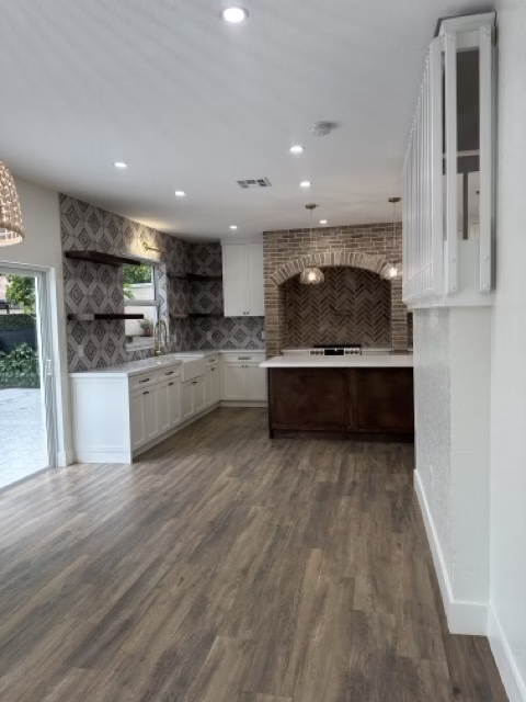 Renovated kitchen with white cabinets, patterned backsplash, and wood floors